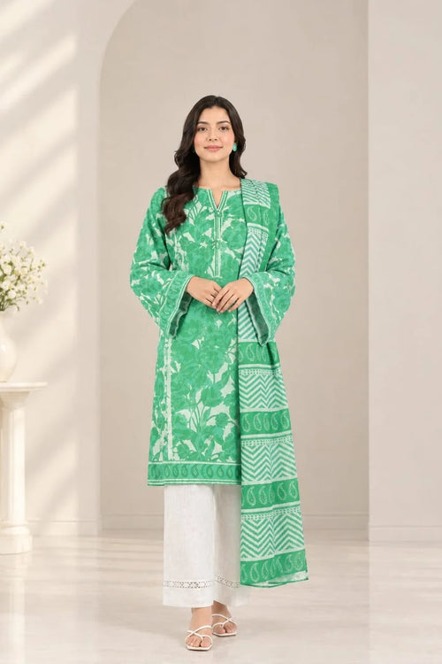 A woman modeling a green and white printed traditional kurta set with white pants, standing in a bright, minimalist interior setting.