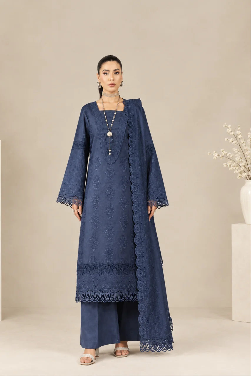 A woman models a dark blue embroidered kurta set with matching wide-leg pants and a sheer embroidered dupatta, set against a neutral beige studio background.